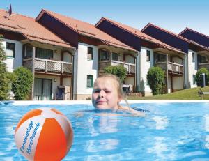 a woman in a swimming pool with a ball at Ferienanlage Harzfreunde in Allrode