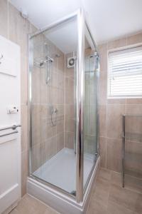 una doccia con porta in vetro in bagno di Puddleduck Cottage ad Aldeburgh
