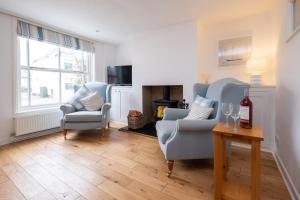 ein Wohnzimmer mit zwei Stühlen und einem Tisch in der Unterkunft Puddleduck Cottage in Aldeburgh