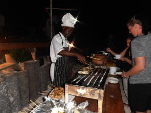 a man cooking food on a grill at a party at Zawadi Beach Villas in Matemwe