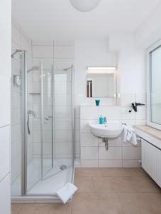 a white bathroom with a shower and a sink at Hotel - Stadtvilla Central in Schweinfurt