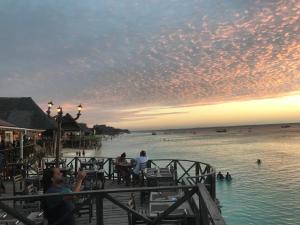 un grupo de personas de pie en un muelle cerca del agua en Langi Langi Beach Bungalows, en Nungwi