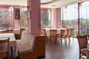 Un comedor con mesas y sillas y ventanas. en Family Hotel Gerdjika, en Plovdiv