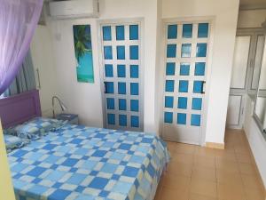 Un dormitorio con una cama azul y blanca en una habitación en Lapiroguevilla[Tourist resident], en Pereybere