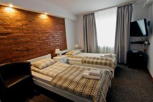 Habitación de hotel con 2 camas y pared de ladrillo en RJ Hotel, en Pabianice