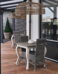 a table and chairs on a porch with a umbrella at Hotel Heer Hugo in Heerhugowaard