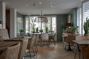a restaurant with tables and chairs and a chandelier at Hotel Heer Hugo in Heerhugowaard