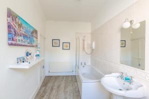 een witte badkamer met een wastafel en een bad bij Ravenscraig House in Staithes