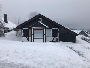 ein schwarzes Haus mit Schnee davor in der Unterkunft Ferienhaus Höhenblick in Winterberg-Langewiese in Winterberg
