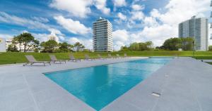 a swimming pool with lounge chairs and some buildings at Torre One II Punta Del Este in Punta del Este
