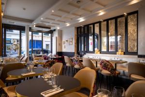 a restaurant with tables and chairs and windows at Hôtel Royal Opéra in Paris