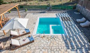 a swimming pool with two chairs and a umbrella at ROGGAKI Ionian Villas in Peratiá