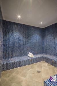 baño de azulejos azules con banco en una habitación en Normas Hotel en Al Khobar