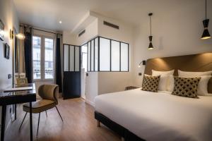 a hotel room with a large bed and a desk at Hôtel Royal Opéra in Paris