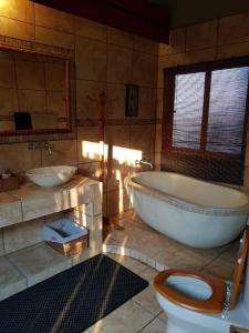 a bathroom with a tub and two sinks and a toilet at Impala Lodge, Mabalingwe in Mabula