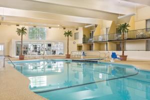 a large pool in a hotel lobby with palm trees at Country Inn & Suites by Radisson, Fergus Falls, MN in Fergus Falls