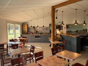 a restaurant with tables and chairs and a kitchen at Mape hôtel in Dampierre-en-Burly