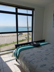 a bedroom with a bed and a view of the ocean at Point Village Accommodation - Santos 40 in Mossel Bay