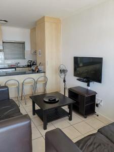 a living room with a couch and a table and a kitchen at Point Village Accommodation - Santos 40 in Mossel Bay