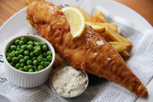 a plate with fish and chips and peas and a lemon at The Riviera Hotel & Apartments - Alum Chine in Bournemouth