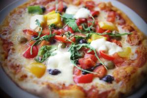 a pizza with vegetables on a plate on a table at The Riviera Hotel & Apartments - Alum Chine in Bournemouth