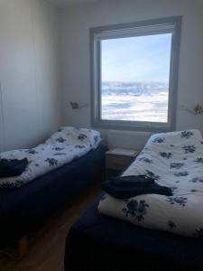 two beds in a room with a window at Vestmannsvatn Guesthouse in Aðaldalur