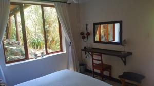 1 dormitorio con cama, espejo y ventana en Lent@Grootbrak en Groot Brak Rivier