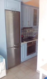 a kitchen with a stainless steel refrigerator and white cabinets at Glyfada Corfu Apartment in Glyfada