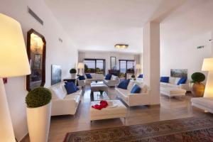 a large living room with white furniture and blue pillows at Hotel Rivage in Sorrento