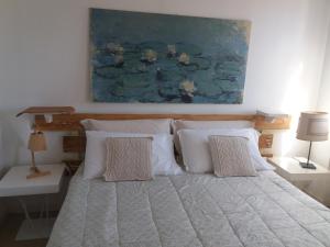 a bed with white pillows and a painting on the wall at A Casa Di Dora in Treviso