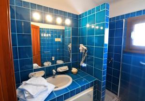 a blue tiled bathroom with a sink and a mirror at Hotel Il Piccolo Golf in Porto Cervo