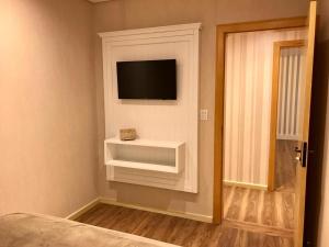 a bedroom with a tv on a wall at Alpen Hospedagem in Treze Tílias