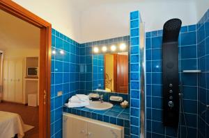 a blue tiled bathroom with a sink and a mirror at Hotel Il Piccolo Golf in Porto Cervo
