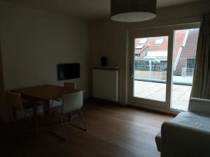 a living room with a table and a sliding glass door at Rooftop apartment with terras - top location in Knokke-Heist