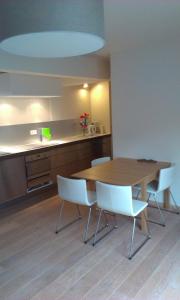 a kitchen with a wooden table and white chairs at Rooftop apartment with terras - top location in Knokke-Heist