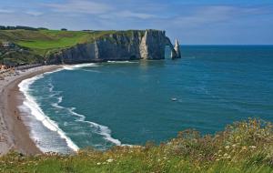 a view of a beach with a large cliff at Le Tout à Pied et son parking privé in Étretat