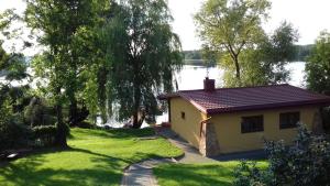 ein kleines Haus im Gras neben einem See in der Unterkunft ZELWAGI 14 in Mikołajki