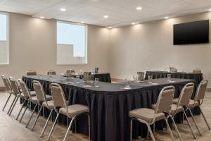 una sala de conferencias con una mesa larga y sillas en Ramada by Wyndham Airdrie Hotel & Suites, en Airdrie