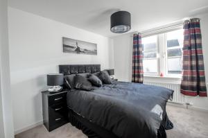 um quarto com uma cama e duas janelas em Orange Apartments Polmuir Gardens Only 7 minutes to City Centre em Aberdeen