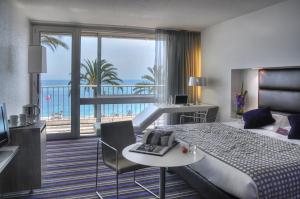 ニースにあるメルキュール ニース プロムナード デ ザングレのベッド付きのホテルルームで、海の景色を望めます。