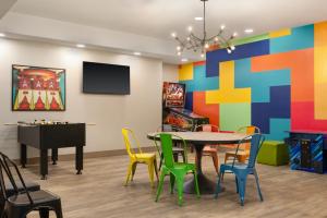 comedor con mesa, sillas y TV en Ramada by Wyndham Airdrie Hotel & Suites, en Airdrie