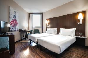 リヴォルノにあるマックス ホテル リボルノの大型ベッドとテレビが備わるホテルルームです。