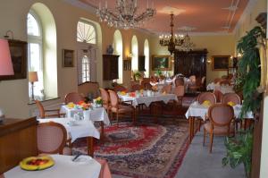 restauracja z białymi stołami i krzesłami oraz żyrandolem w obiekcie Hotel Fürstenhof w mieście Rathenow