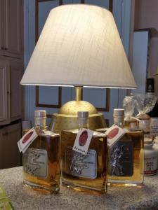 trois bouteilles de whisky assises sur une table avec une lampe dans l'établissement Logis Hôtel de la Tête Noire, à Autun
