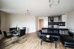 sala de estar con sofá negro y mesa en City Centre Orange Apartments - Portland Street, en Aberdeen