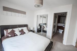 a bedroom with a large white bed and a bathroom at City Centre Orange Apartments - Portland Street in Aberdeen