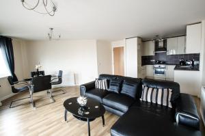 sala de estar con sofá negro y mesa en City Centre Orange Apartments - Portland Street, en Aberdeen