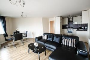 a living room with a black couch and a table at City Centre Orange Apartments - Portland Street in Aberdeen