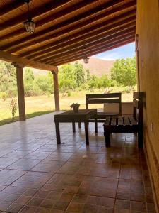 patio con bancos, mesa y vistas en Finca Las Pircas Casa de Adobe, en Famatina