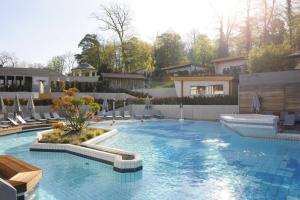 une grande piscine avec des chaises et une maison dans l'établissement Villa Welcome, à Mondorf-les-Bains